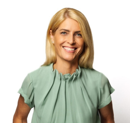 blonde woman in pale green blouse smiling at camera